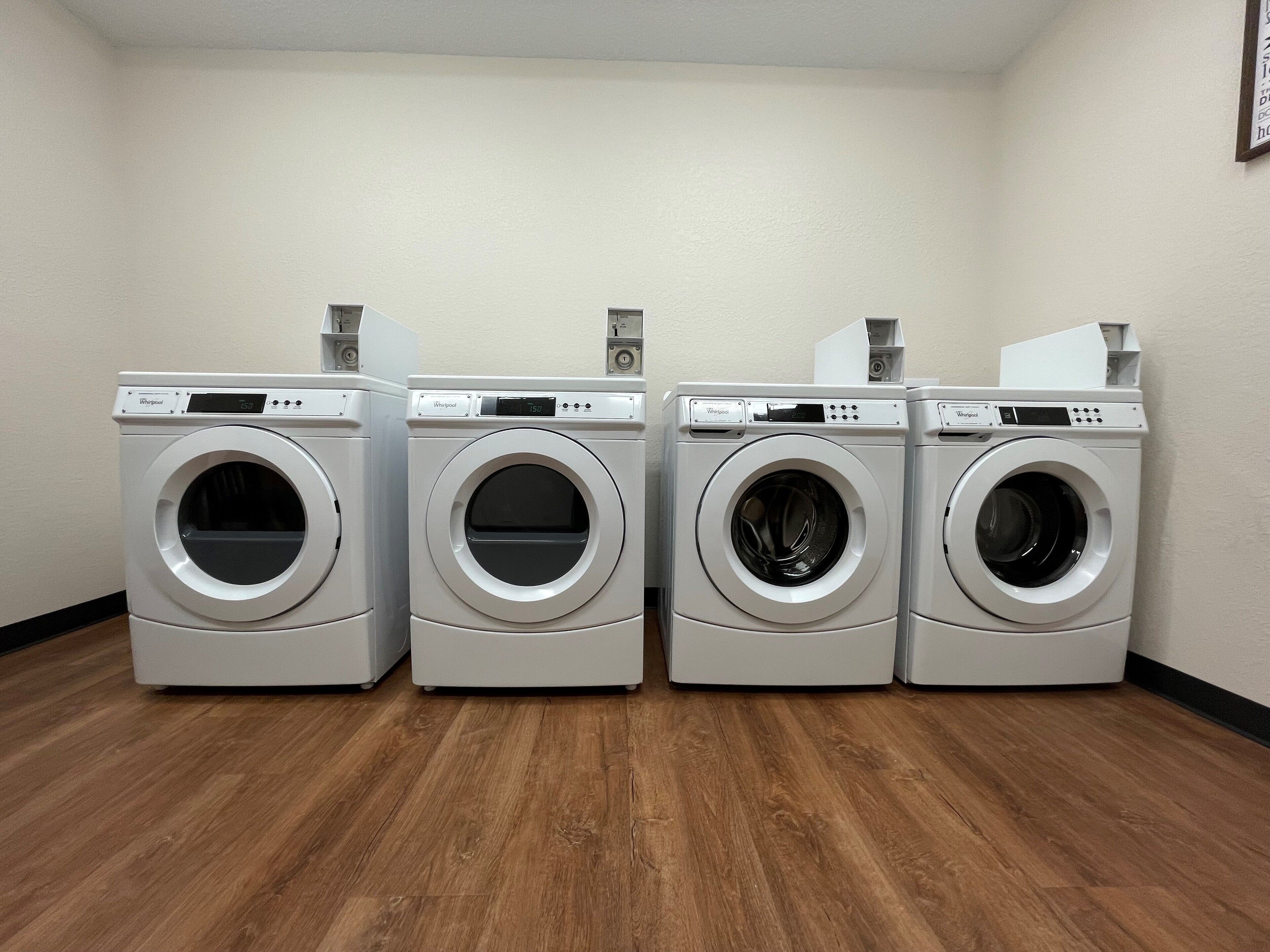 A laundry room with four Whirlpool washers and dryers.