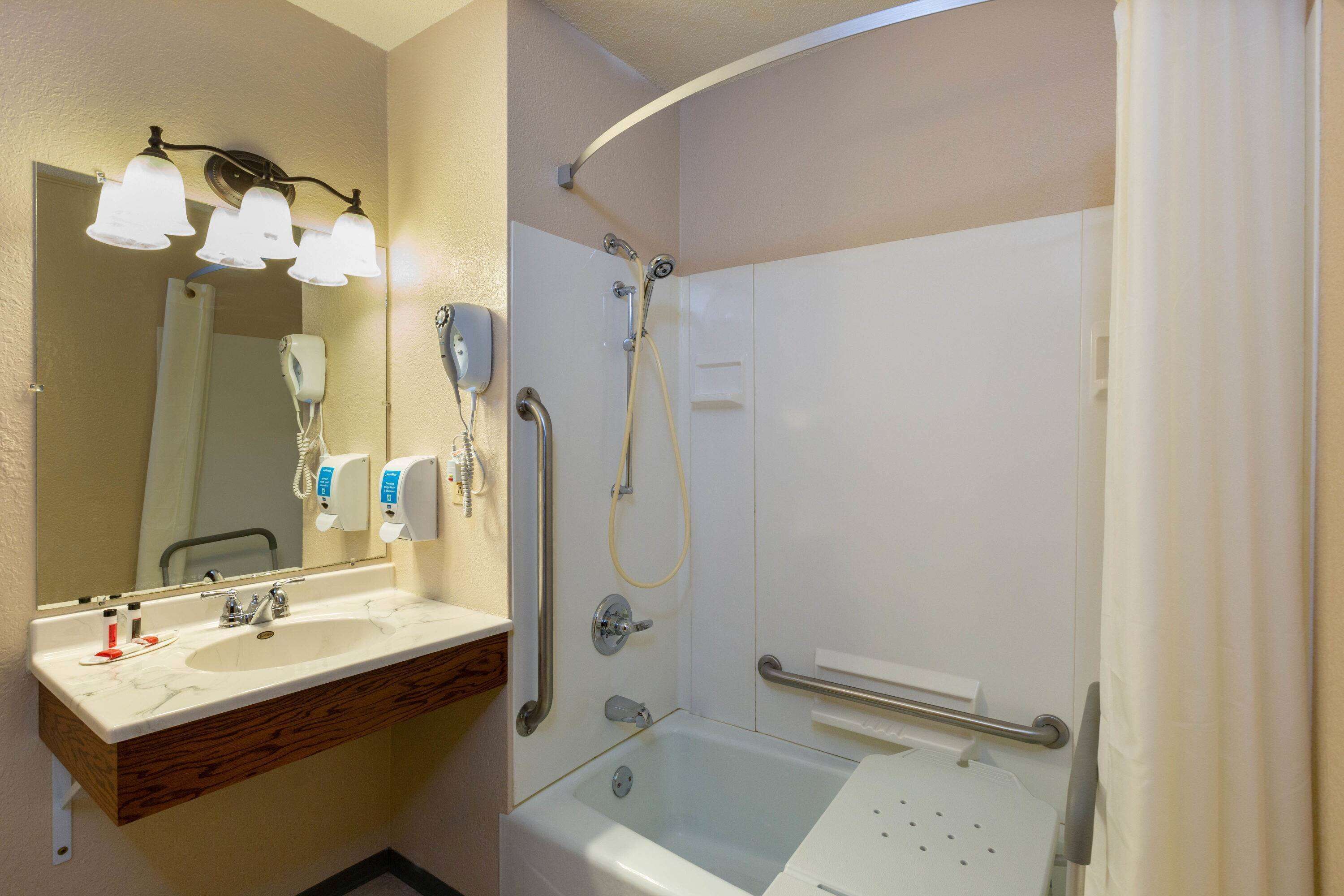 A bathroom with a sink, mirror, and shower.