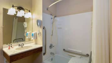 A bathroom with a sink, mirror, and shower.