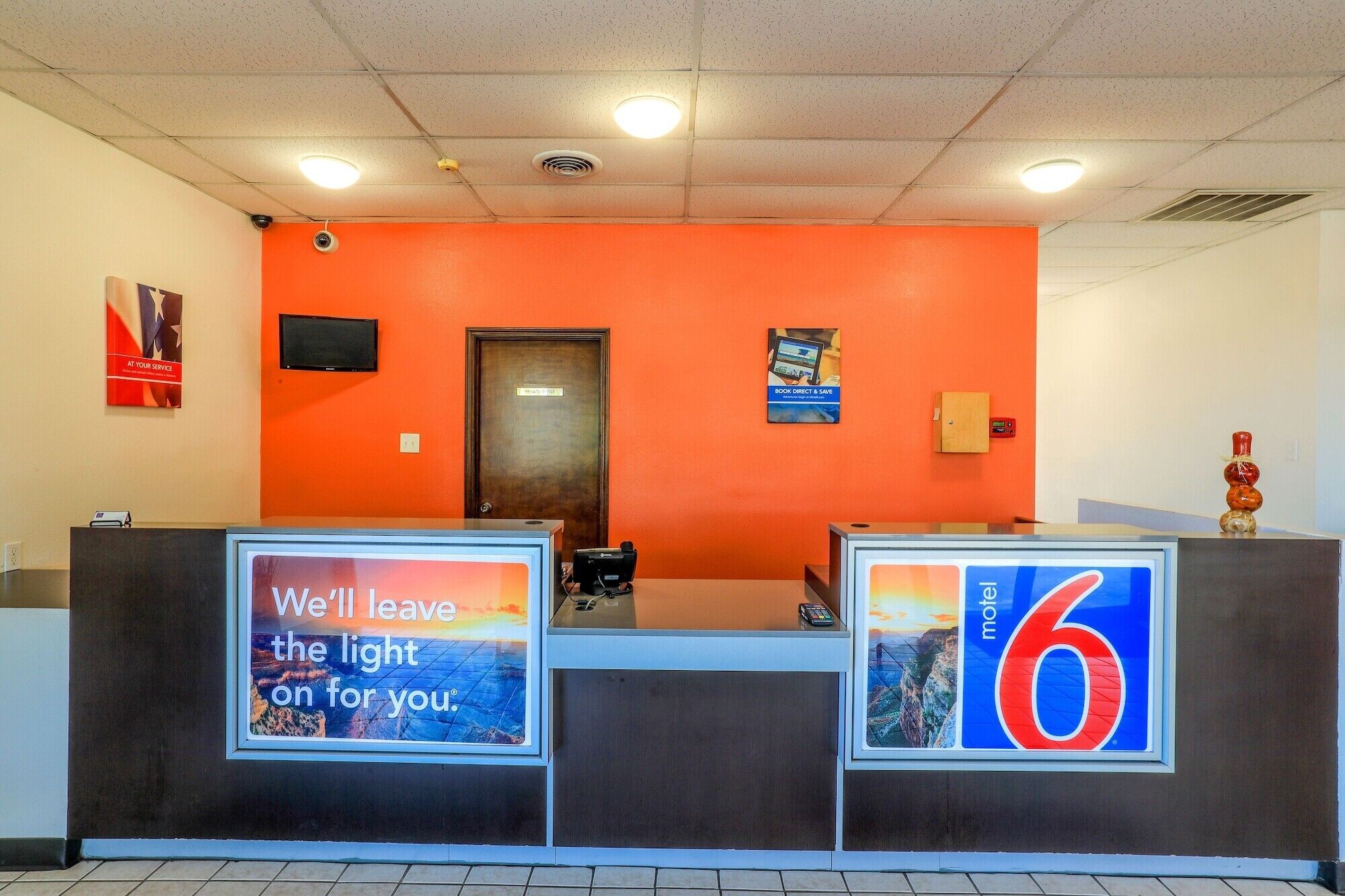 Une salle d’attente avec un mur orange, une porte en bois et deux grandes enseignes indiquant une zone de service d’un rayon de 9,6 kilomètres.