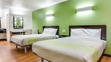 A hotel room with two beds, a desk, a chair, and a mirror.