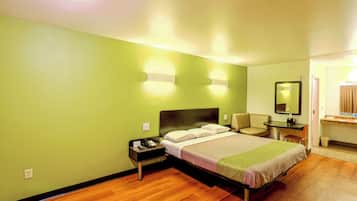 A hotel room with a bed, a nightstand, a desk, and a chair.