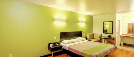 A hotel room with a bed, a nightstand, a desk, and a chair.