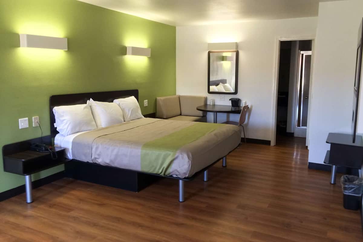 A hotel room with a bed, bedside tables, a desk, and a chair.