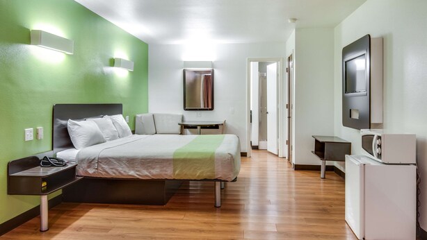 Une chambre d’hôtel équipée d’un lit, d’une table de chevet, d’une lampe et d’un téléviseur fixé au mur.