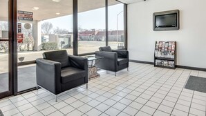 Un'area reception con due poltrone nere, un tavolino, una TV a parete e un espositore per riviste.