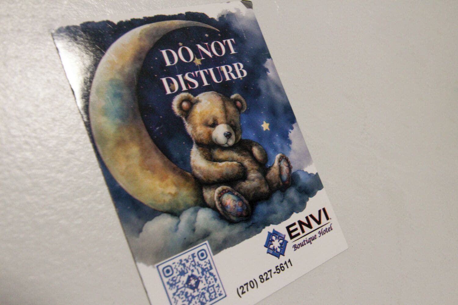 A 'DO NOT DISTURB' sign with a bear on a crescent moon, and the ENVI Boutique Hotel logo with a QR code.