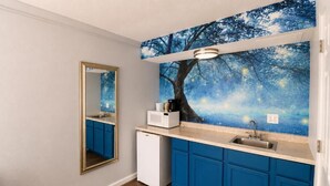 A kitchen with blue cabinets, a white refrigerator, a microwave, and a sink. - Envi Boutique Hotel Henderson-Evansville South (Henderson)