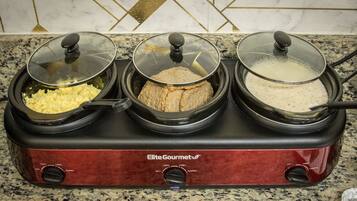 A three-compartment slow cooker with lids, labeled "Elite Gourmet," on a granite countertop.