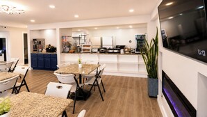A modern kitchen with built-in appliances, a dining area with a granite table, and a large TV mounted on the wall. - Envi Boutique Hotel Henderson-Evansville South (Henderson)