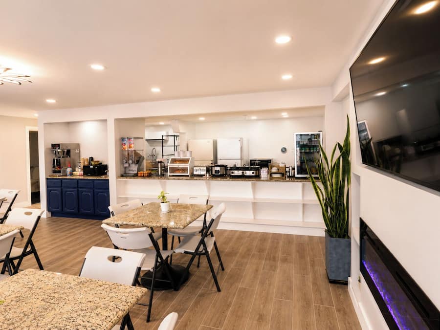 Una cocina moderna con electrodomésticos integrados, un comedor con mesa de granito y un televisor grande montado en la pared.