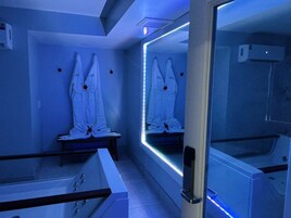 Una habitación con un separador de vidrio, una bañera y dos toallas blancas colgadas en la pared.