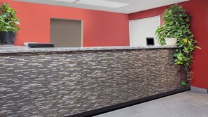 A reception area with a stone-patterned wall, a reception desk, and potted plants. - Super 8 by Wyndham Logansport (Logansport)