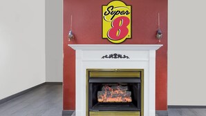 A fireplace with a Super 8 logo above it, a white mantel, and a black and gold frame. - Super 8 by Wyndham Logansport (Logansport)