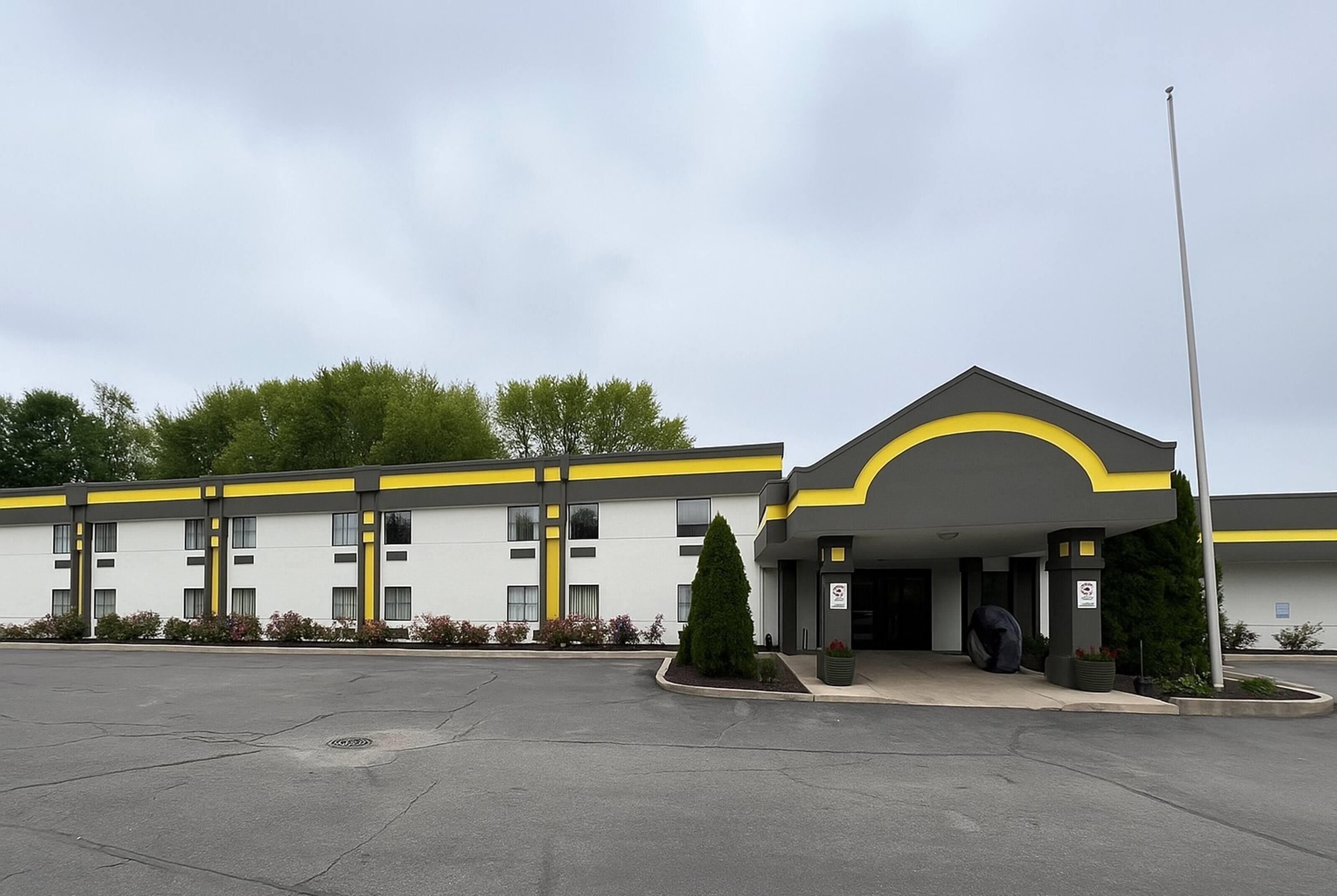 A hotel with a modern design, featuring a prominent yellow and grey color scheme, a covered entrance, and a parking lot.