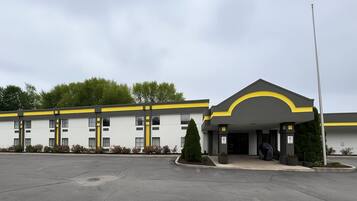 A hotel with a modern design, featuring a prominent yellow and grey color scheme, a covered entrance, and a parking lot.