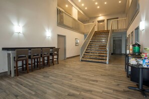 A spacious kitchen with wooden flooring, a staircase, and a bar area with stools.