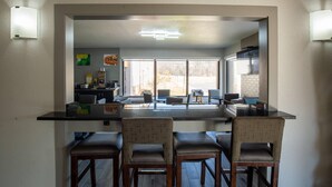 A kitchen with a bar area, two bar stools, and a view of the outside. - Quality Inn & Suites Portage Central (Portage)