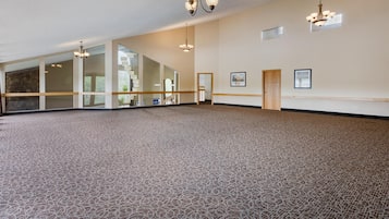 Una habitación amplia con alfombra estampada, ventanas grandes y varios candelabros.