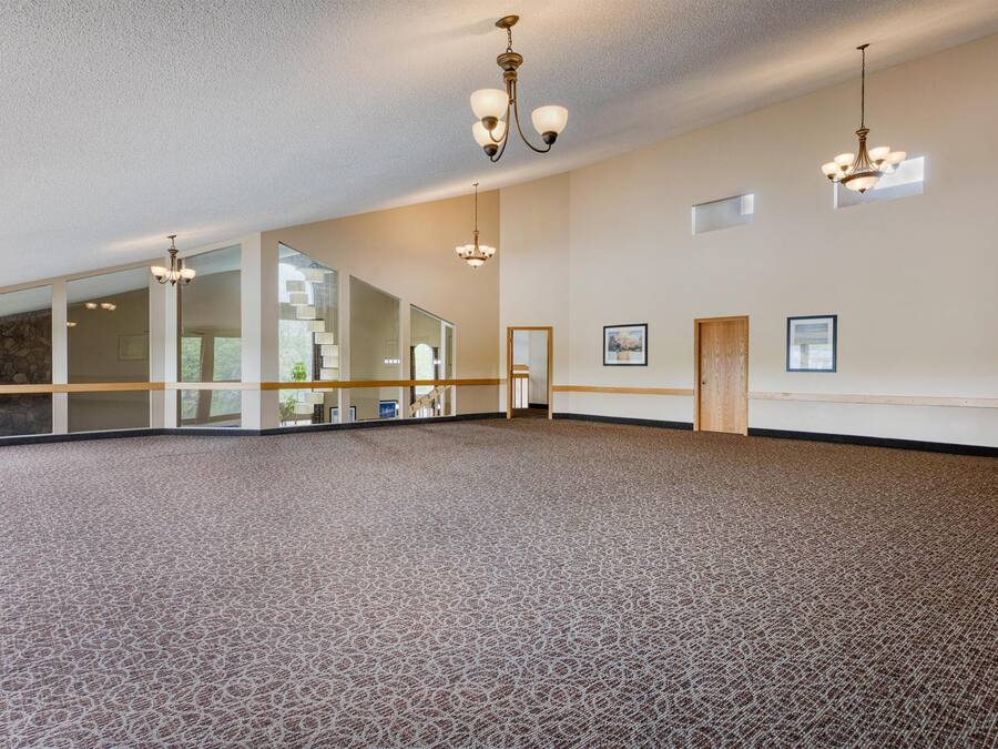 Una habitación amplia con alfombra estampada, ventanas grandes y varios candelabros.