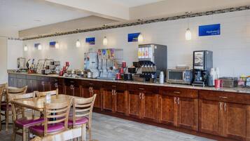 A hotel kitchen with a long counter, coffee machines, and a refrigerator.