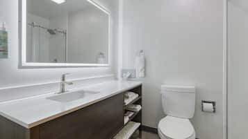 A modern bathroom with a large mirror, a white sink, a toilet, and a shower area.