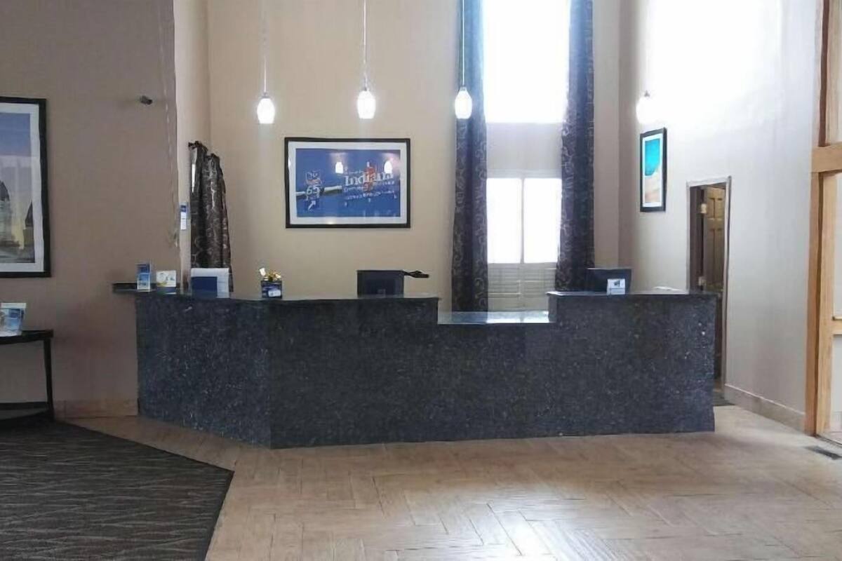 A reception desk with a dark marble top, a framed cityscape picture above it, and a wooden floor.