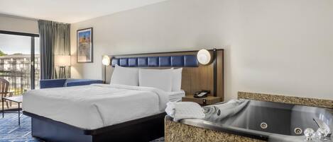 A hotel room with a bed, a bathroom with a bathtub, a desk, and a chair.