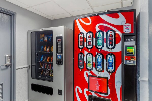 A vending machine with various beverages and snacks, a Coca-Cola branded machine, and a digital payment interface.