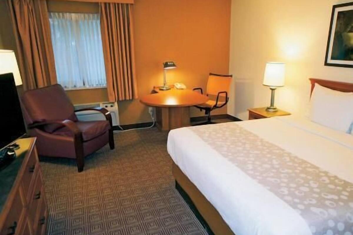 Une chambre d’hôtel avec un lit, un bureau, une chaise et une lampe.