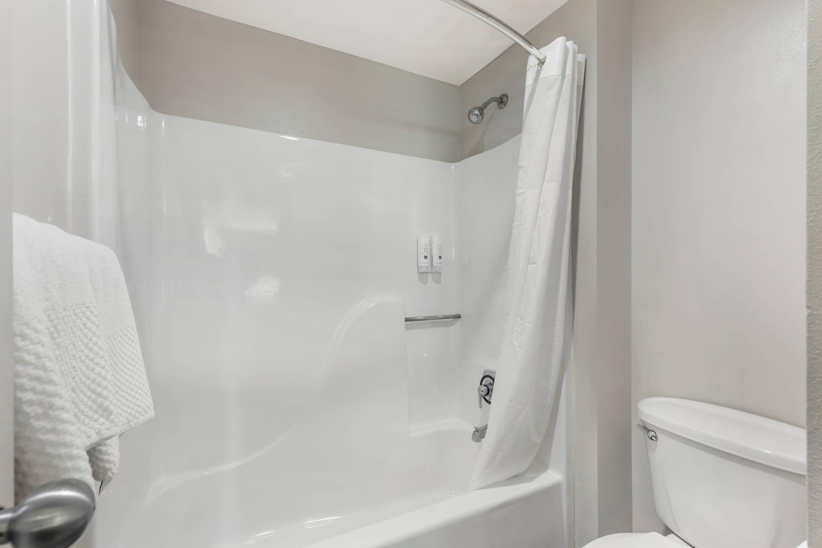 A modern bathroom with a glass-enclosed shower, a white toilet, and a towel hanging on the wall.