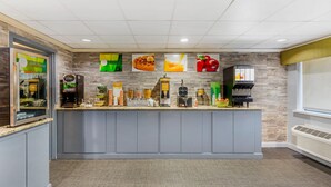 A modern kitchen area with a built-in coffee station, a refrigerator, and a microwave.