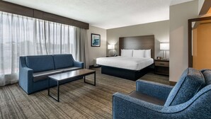 Una habitación de hotel con una cama, un sofá, una silla, un escritorio y una lámpara.