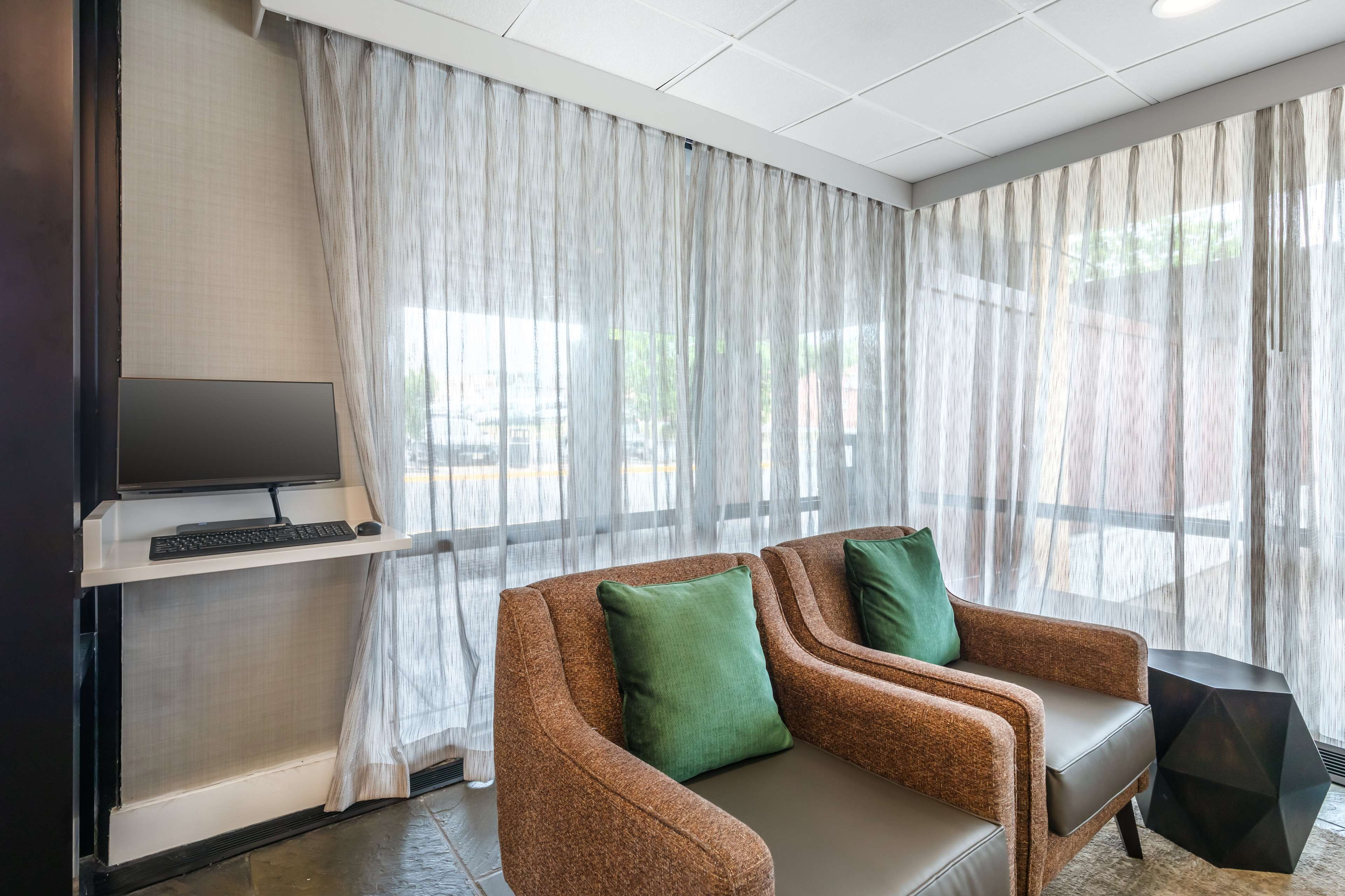A modern room with a brown sofa, a TV on a stand, and sheer curtains.