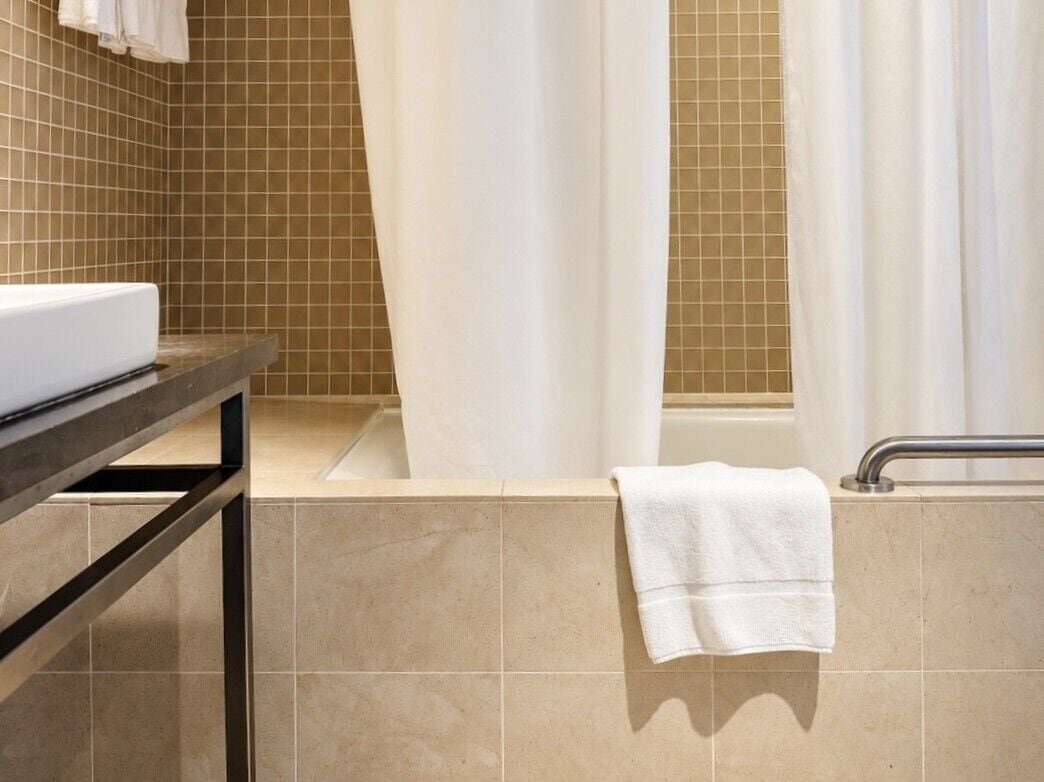 Un baño con lavamanos, toallero y bañera.
