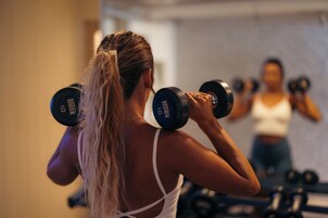 A person exercising with dumbbells in a gym.