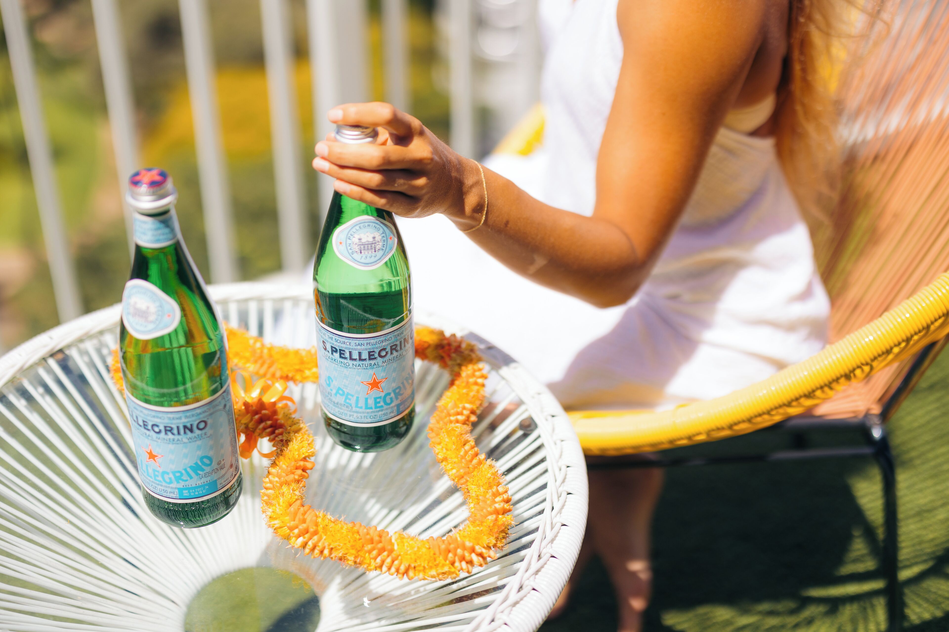 A person holding a bottle of S. Pellegrino sparkling mineral water.