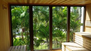 A room with large windows offering a view of lush greenery and palm trees. - Hotel La Croix (Honolulu)
