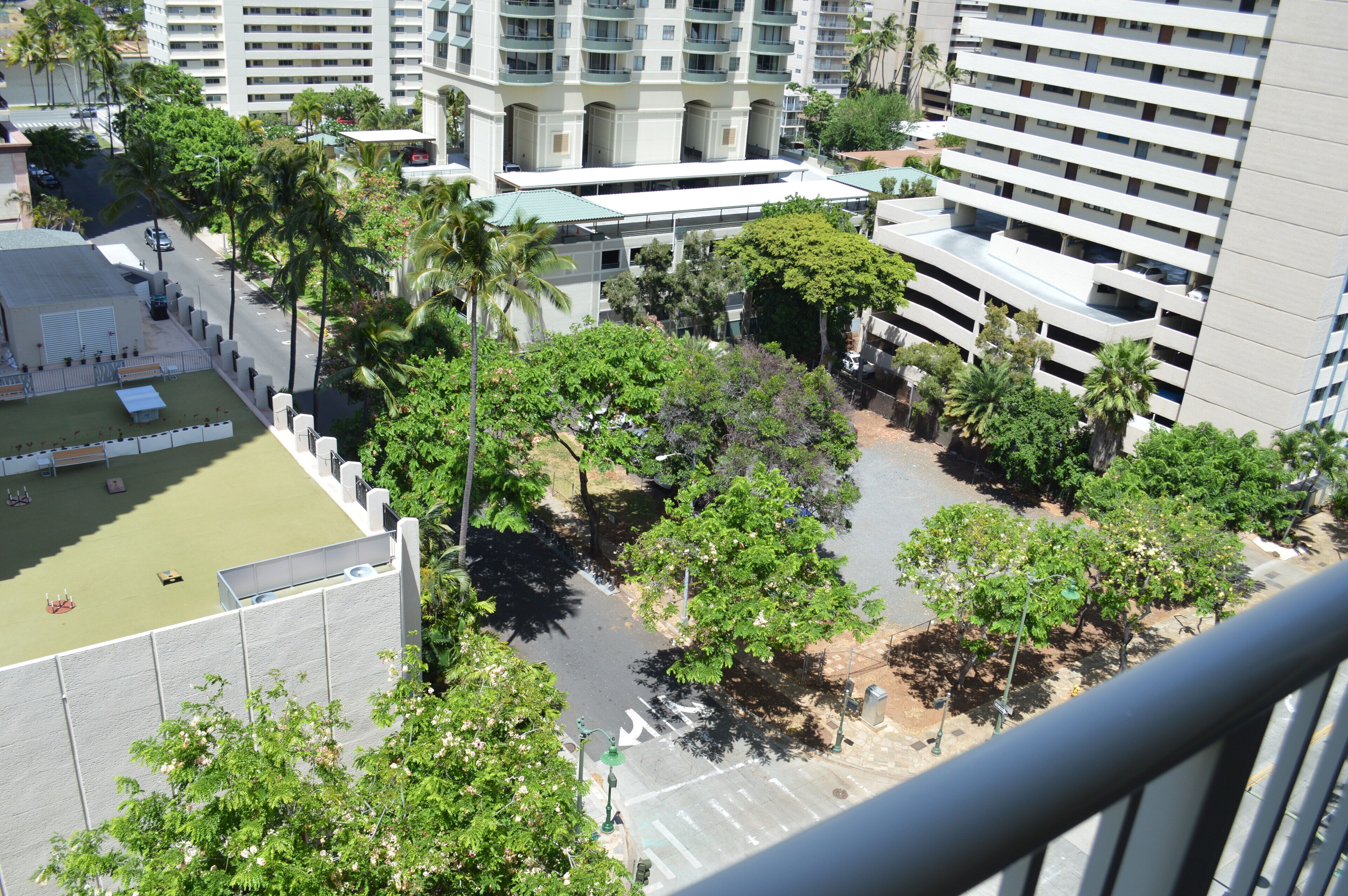 Un edificio de gran altura con múltiples balcones y un patio rodeado de árboles.