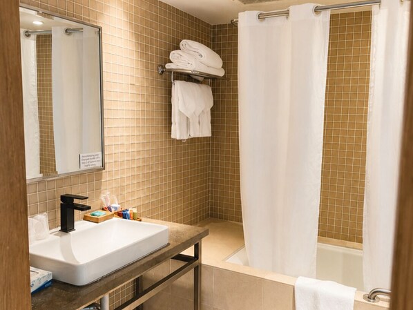 Une salle de bain équipée d’un lavabo, d’un miroir, d’un porte-serviettes et d’un rideau de douche.