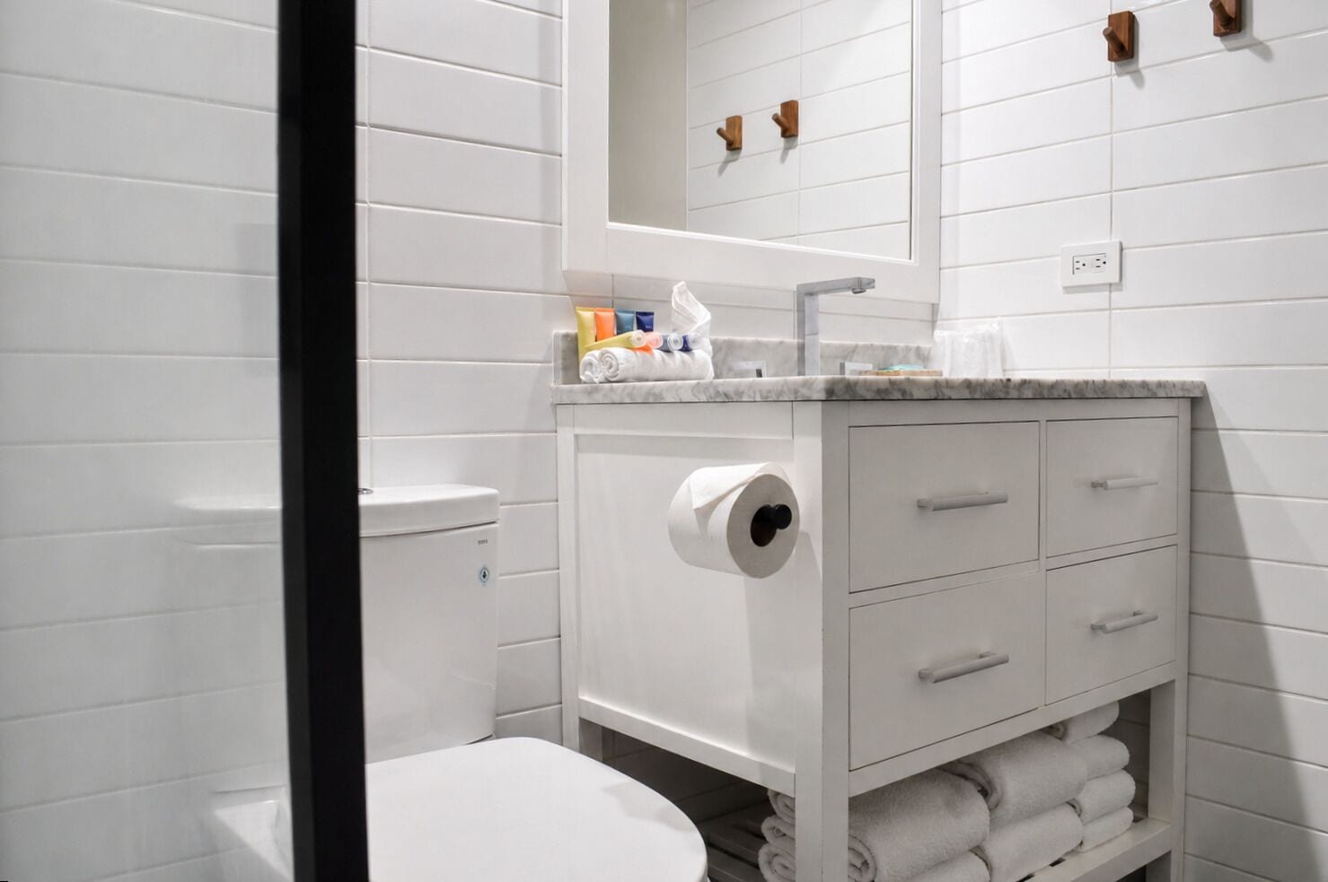 A bathroom with a toilet, a sink with a marble countertop, a mirror, and a towel rack.