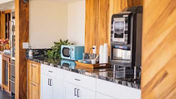 Een moderne keuken met houten kastjes, een marmeren aanrechtblad en een ingebouwde magnetron.