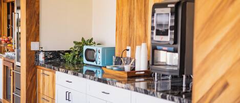 Een moderne keuken met houten kastjes, een marmeren aanrechtblad en een ingebouwde magnetron.