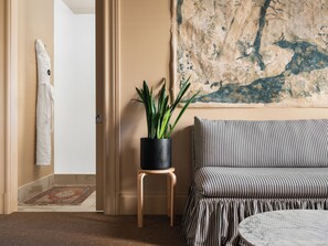 A room with a striped sofa, a round table, a potted plant, and a painting on the wall. - Palihotel San Francisco (San Francisco)