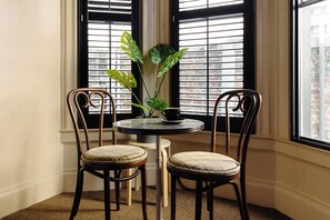 A corner room with a round table, two chairs, a potted plant, and a window with blinds. - Palihotel San Francisco (San Francisco)