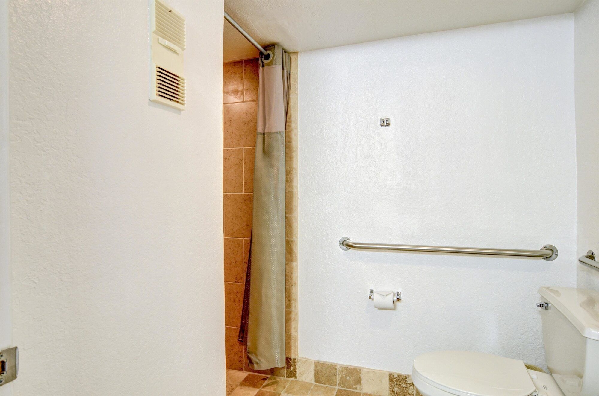 A bathroom with a white toilet, a shower with a glass door, and a towel rack.