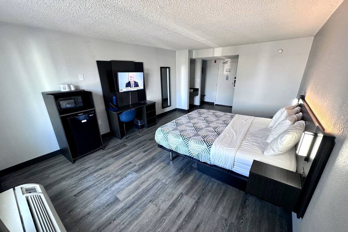Ein Hotelzimmer mit Bett, Schreibtisch, Fernseher, Mikrowelle und kleinem Kühlschrank.