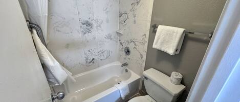 Un baño con bañera, inodoro y ducha.