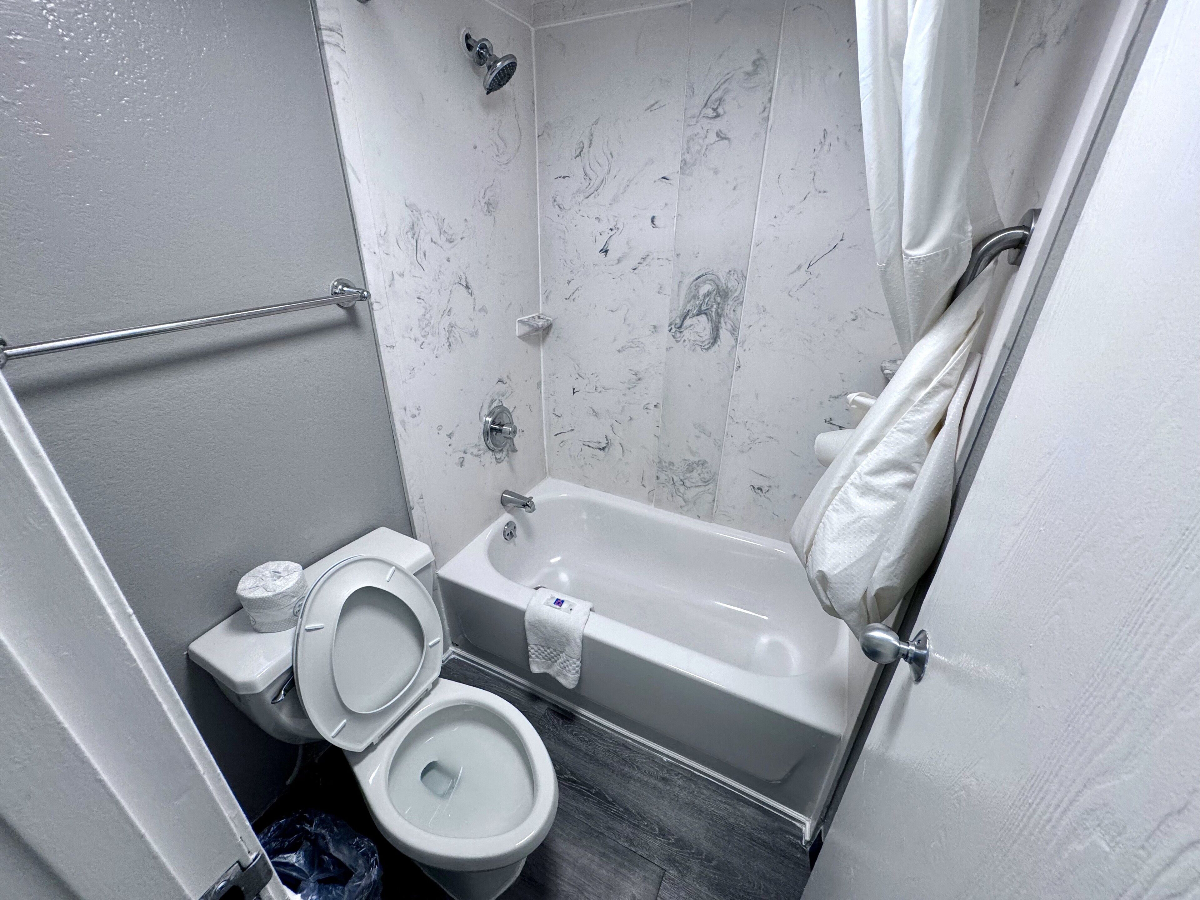A bathroom with a toilet, bathtub, and shower.