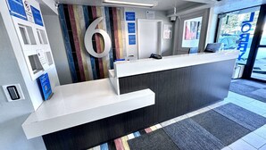Un mostrador de recepción con un cartel grande con el número 6, una barra blanca y una pared de rayas de colores.